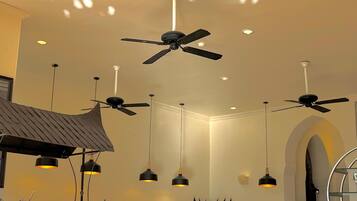 A modern kitchen with ceiling fans, pendant lights, and a buffet setup.