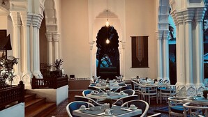 A restaurant with a long dining area, white columns, and tables set for dining. - Monopoli Hotel Bukittinggi (Bukittinggi)