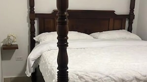 Una cama con dosel de madera y ropa blanca.