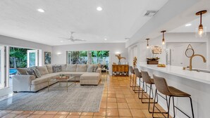 A spacious living room with a large sectional sofa, a coffee table, and a bar area with stools. - Heated pool / Quiet Neighborhood / Family Vacation / Escape Key (Fort Lauderdale)