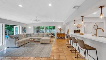 A spacious living room with a large sectional sofa, a coffee table, and a bar area with stools.