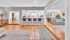 A spacious living area with a kitchen island, bar stools, and a sofa. - Heated pool / Quiet Neighborhood / Family Vacation / Escape Key (Fort Lauderdale)