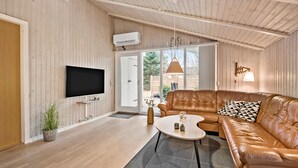Un salon moderne avec un canapé en cuir, un téléviseur à écran plat et une grande fenêtre.