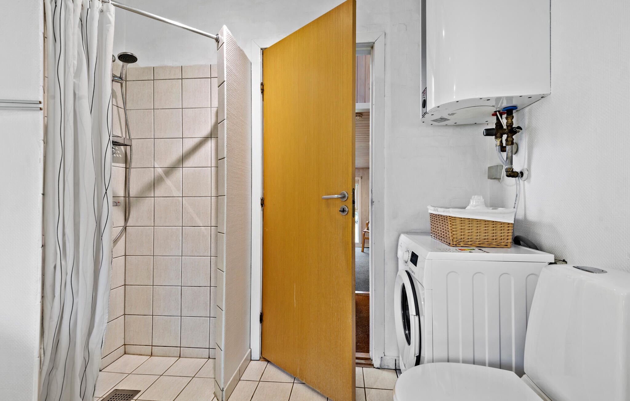 Et badeværelse med bruser, toilet, vaskemaskine og en radiator.