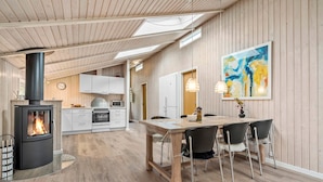 Une cuisine moderne dotée d’un poêle à bois, de meubles blancs et d’un coin repas avec une table et des chaises.
