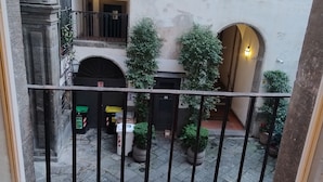 A courtyard with stone flooring, potted plants, and a metal railing. - Luxury Apartment in historical 15th century building (Napoli)