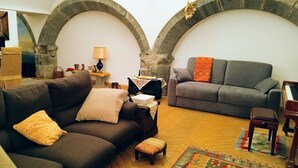 A cozy living room with two sofas, a wooden floor, and a piano. - Luxury Apartment in historical 15th century building (Napoli)