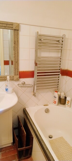 Een badkamer met een wastafel, spiegel, handdoekhouder en ligbad.