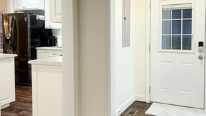 Une cuisine moderne avec des meubles blancs, un réfrigérateur noir et un four en acier inoxydable.