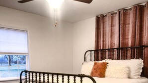 Une chambre à coucher avec un cadre de lit en bois foncé, du linge de lit blanc et un ventilateur de plafond.