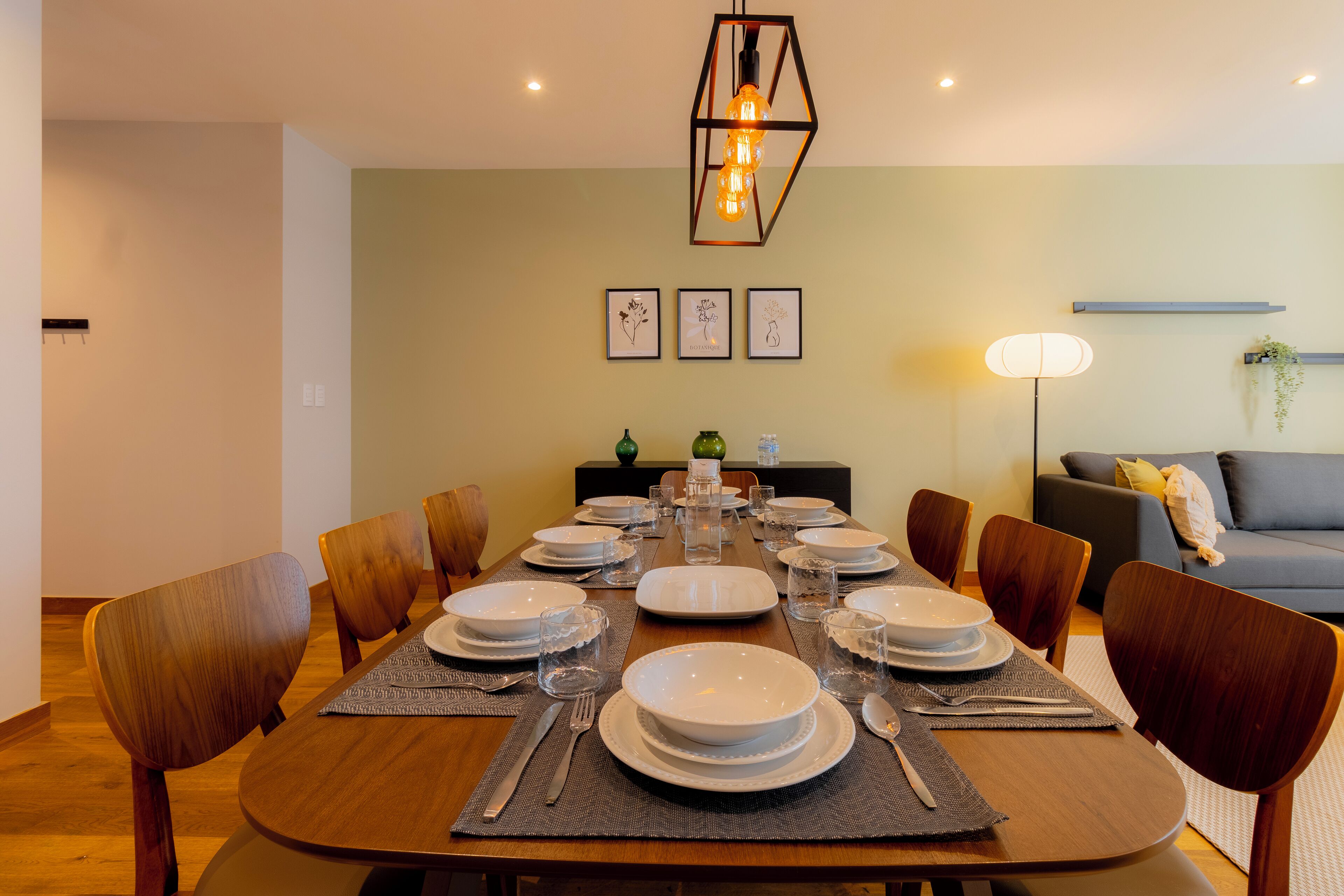 Comedor con una larga mesa de madera dispuesta para seis personas, rodeada de sillas de madera.