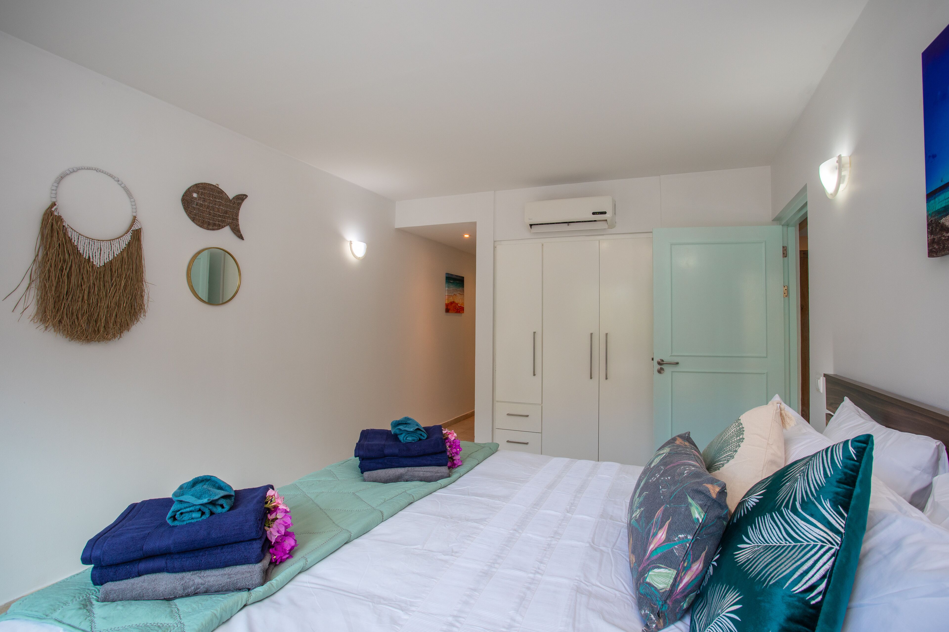 Une chambre à coucher comprenant un lit, une armoire, un miroir et des éléments de décoration murale.