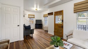 Un salon spacieux doté d’un parquet, d’un canapé, d’un fauteuil et d’un téléviseur.