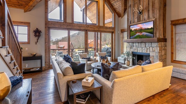 A spacious living room with a stone fireplace, large windows, and a cozy seating area.