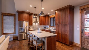 A modern kitchen with wooden cabinets, stainless steel appliances, and a central island with bar stools.