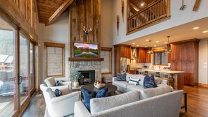 A spacious living room with a stone fireplace, a large flat-screen TV, and a cozy seating area.