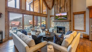 A spacious living room with a stone fireplace, large windows, and a cozy seating area.