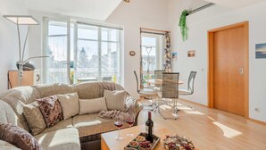 Una sala de estar moderna con un sofá modular, una mesa de comedor con sillas, una botella de vino y una bandeja de aperitivos.