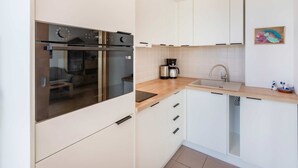 Moderni keittiö, jossa on sisäänrakennettu uuni, kahvinkeitin ja pesuallas.