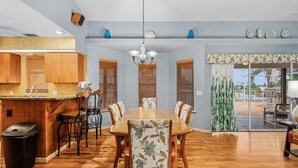 A dining area with a wooden table and chairs, a chandelier, and a view of the outdoors through a sliding glass door. - 3/2 Pool Home in St. James, Gorgeous Views! (Saint James City)