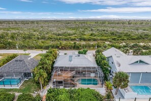 A modern house with a large deck, a swimming pool, and a view of a natural landscape.