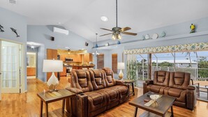 A spacious living room with a brown leather sofa, two side tables, and a ceiling fan. - 3/2 Pool Home in St. James, Gorgeous Views! (Saint James City)
