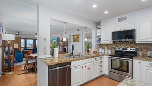 Una cocina moderna con armarios blancos, electrodomésticos de acero inoxidable y una encimera de granito.