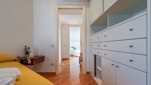 Une chambre à coucher comprenant un lit, une table de chevet, une commode et un couloir menant à une autre pièce.