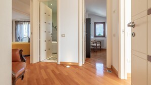 Une pièce spacieuse avec un plancher en bois, un fauteuil en cuir marron et une vue sur une salle de bain dotée d’une douche carrelée.