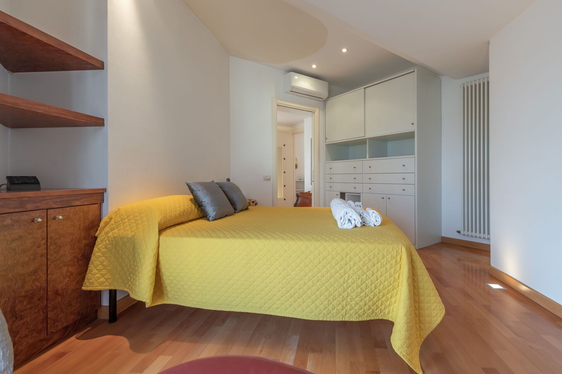 A bedroom with a bed, wooden dresser, and a walk-in closet.