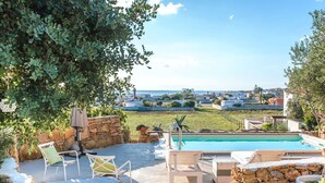A poolside area with stone walls, lounge chairs, and a view of the sea and buildings in the distance. - Wonderful private villa for 6 guests with private pool, A/C, WIFI, TV and terrace (Torricella)