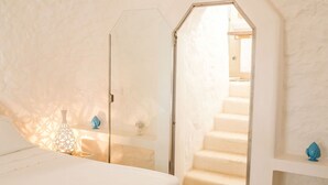 A bedroom with a bed, a nightstand, a decorative vase, and a door leading to a staircase. - Wonderful private villa for 6 guests with private pool, A/C, WIFI, TV and terrace (Torricella)