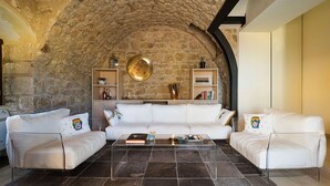 Ein Wohnzimmer mit Steinwand, weißen Sofas, einem Couchtisch und Regalen mit Dekoration.