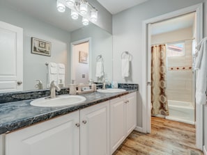 A bathroom with two sinks, a large mirror, and a shower area. - Mid-Sand Creek (Colorado Springs)
