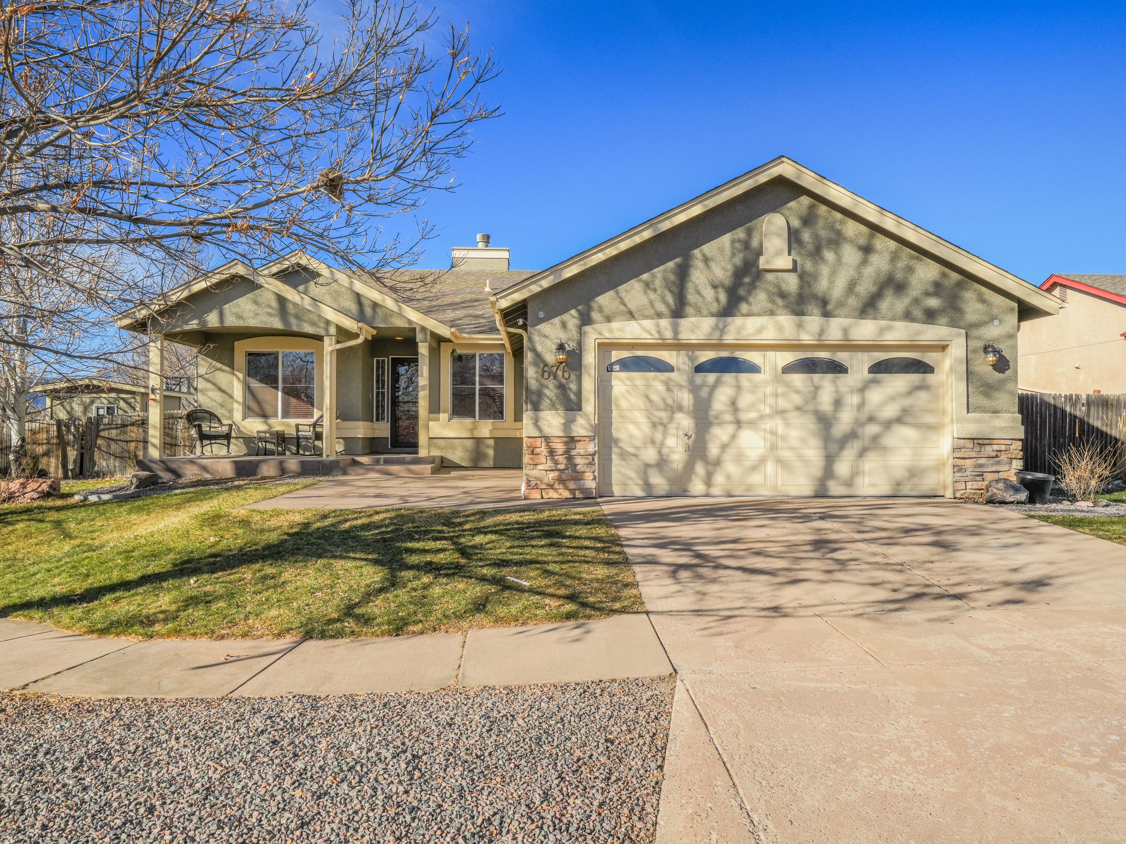 A two-story house with a garage, a covered porch, and a well-maintained lawn.