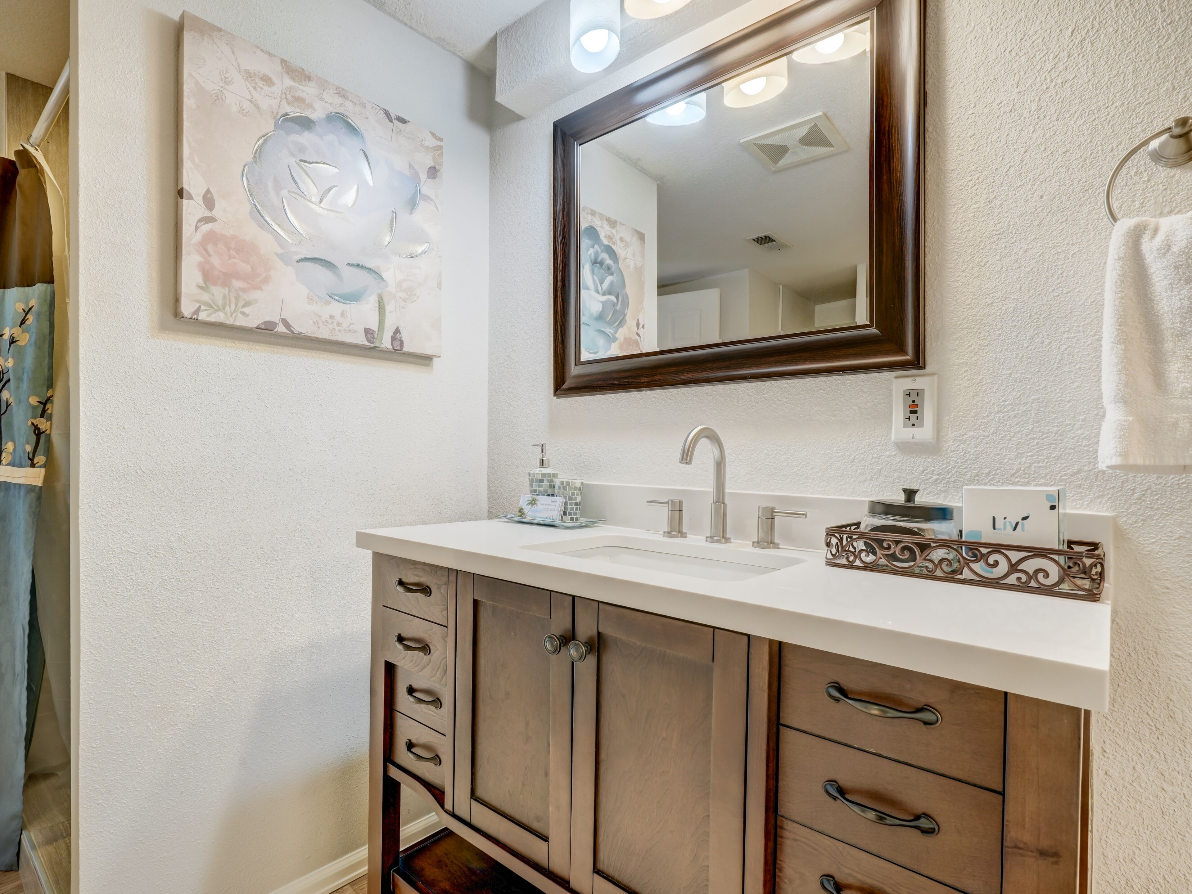 Un baño con un lavamanos blanco, un espejo grande y un mueble con cajones.