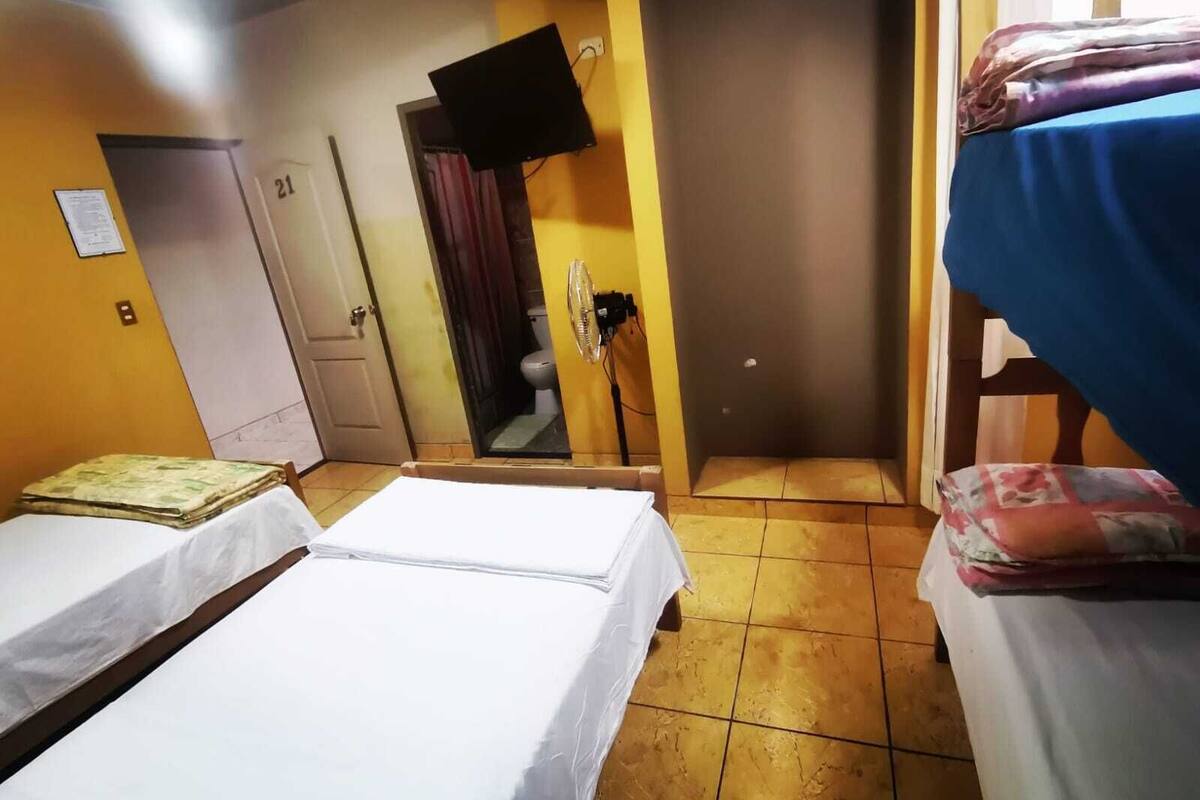 Une chambre d’hôtel avec deux lits, une salle de bain et un téléviseur fixé au mur.