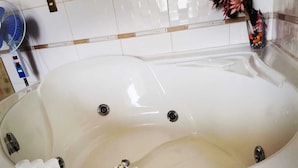A bathtub with a control panel, a bottle of lotion, and a card. - HOTEL LOS ANGELES (Huaral)