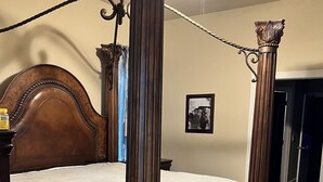 Une chambre à coucher avec un lit à baldaquin, un ventilateur de plafond et un tableau encadré au mur.