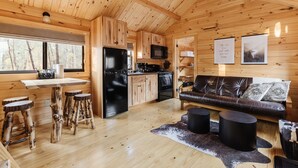 Een houten chalet van binnen met een keuken, een eetgedeelte en een woonkamer.
