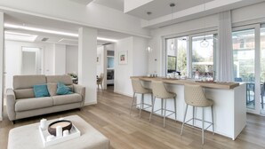 A modern living room with a sofa, a coffee table, and a kitchen area with bar stools.
