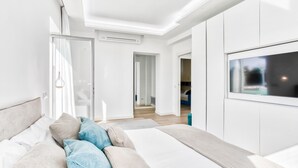 A modern bedroom with a bed, pillows, and a TV.