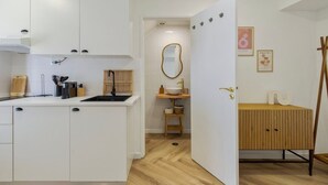 A modern kitchen with white cabinetry, a black sink, and wooden accents. - Felp Santa Maria 1 (Setúbal)