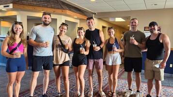 A group of people standing in a hotel lobby with a patterned carpet, a ceiling with recessed lighting, and a visible wall with a textured finish.