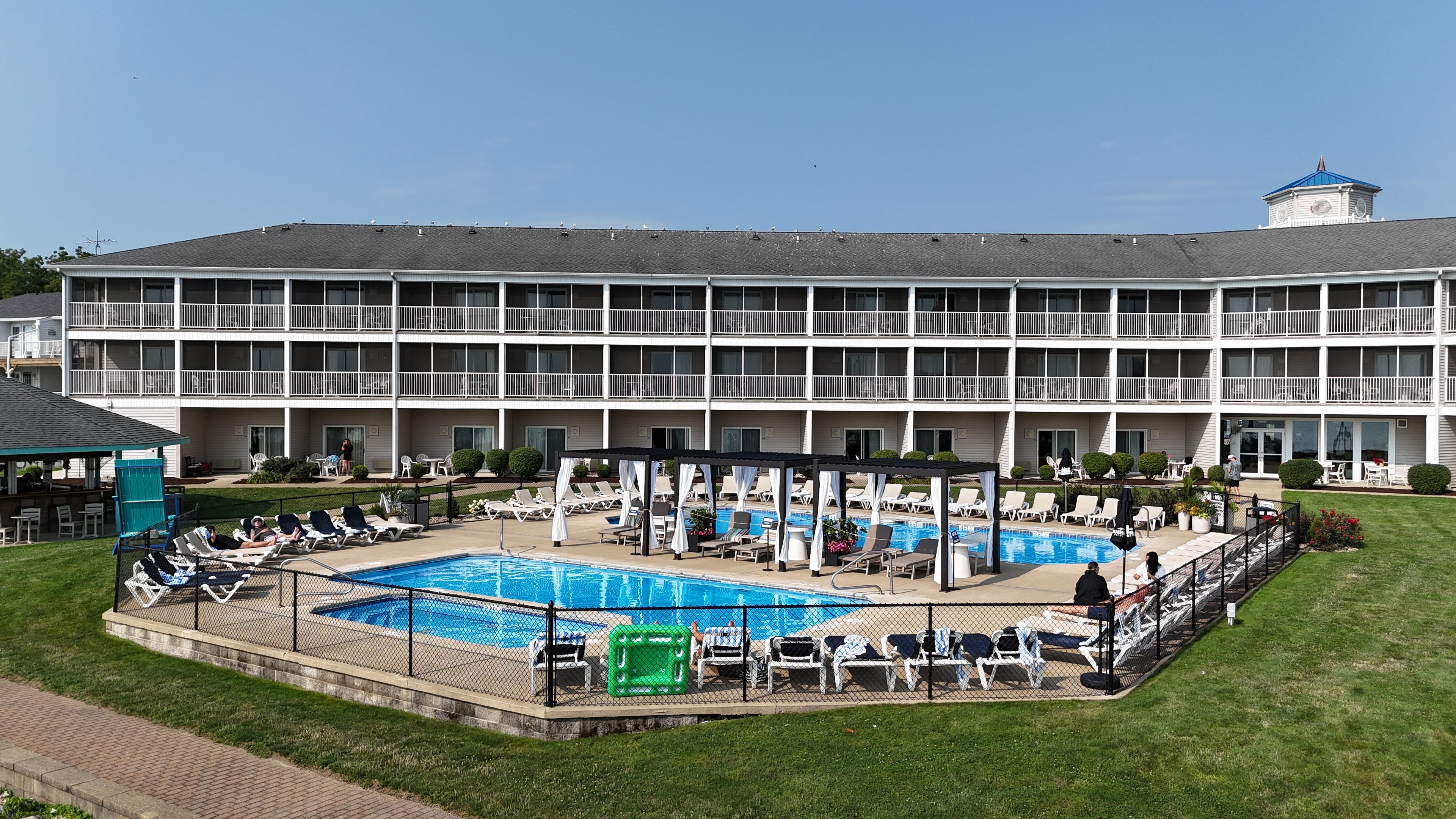 Un hôtel doté d’une piscine, de plusieurs balcons et d’un espace salon couvert.