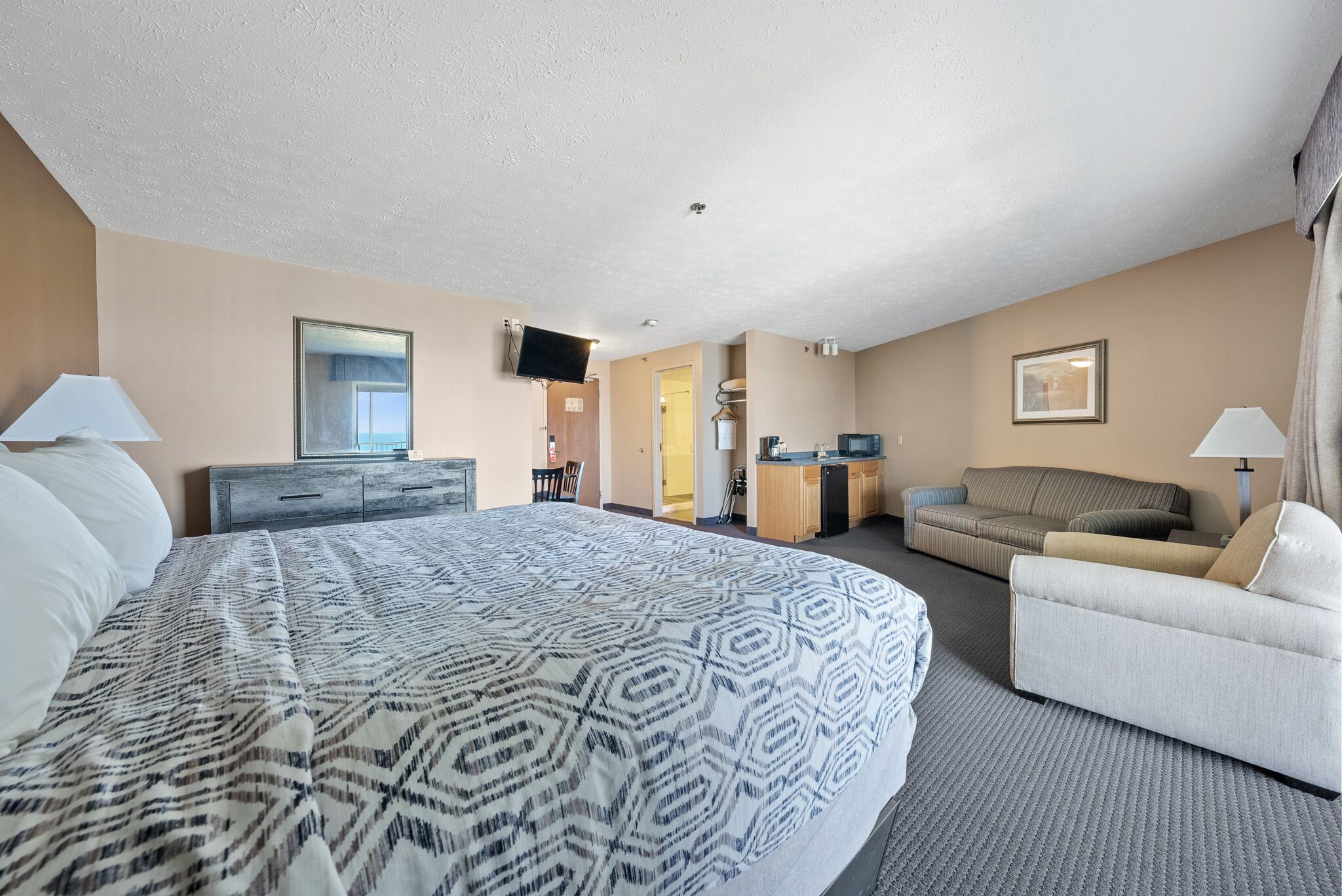 Une chambre d’hôtel avec un grand lit, un canapé, un bureau et une télévision.