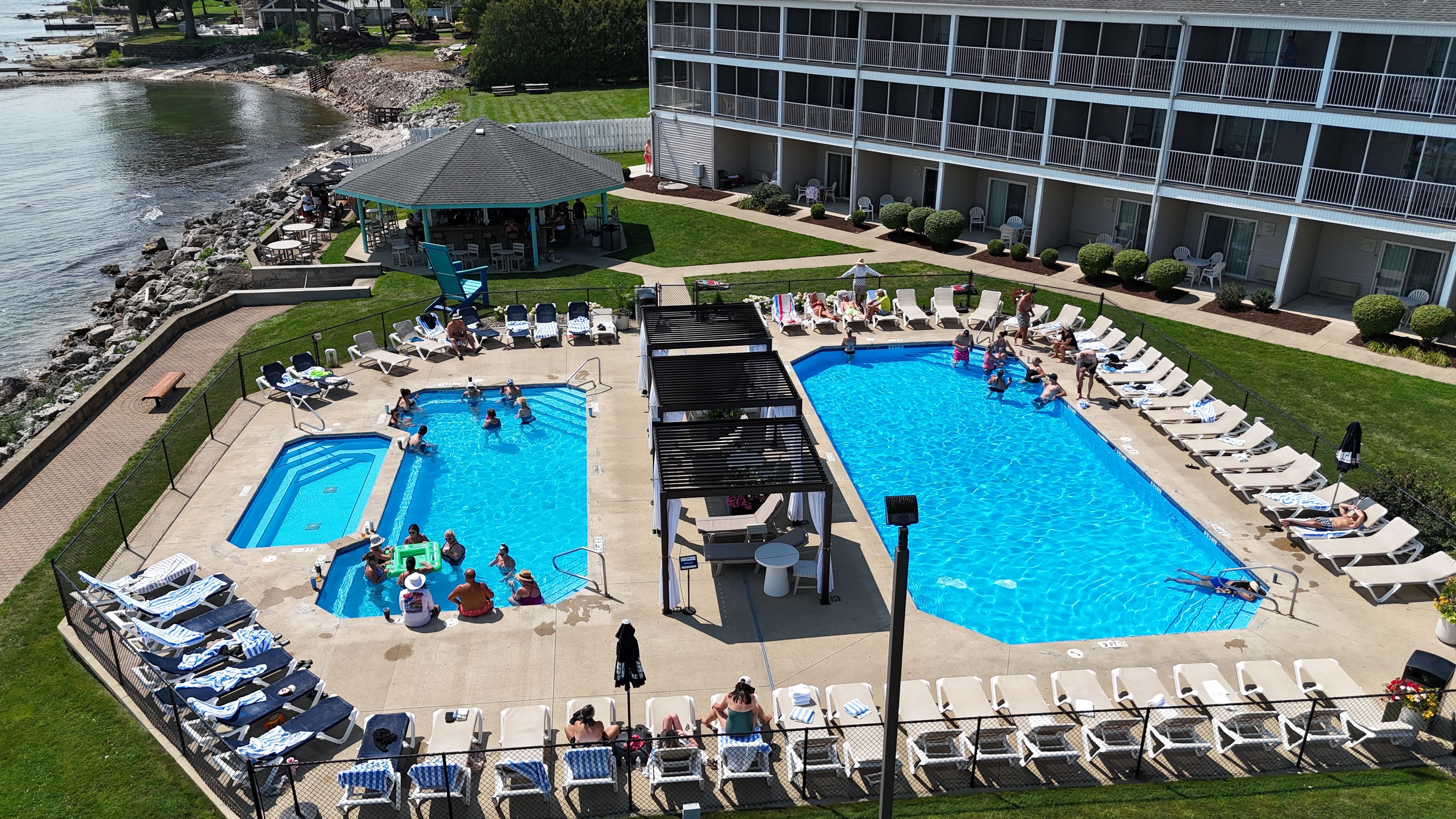 Un hôtel doté de deux piscines, de chaises longues et d’un bâtiment avec des balcons.