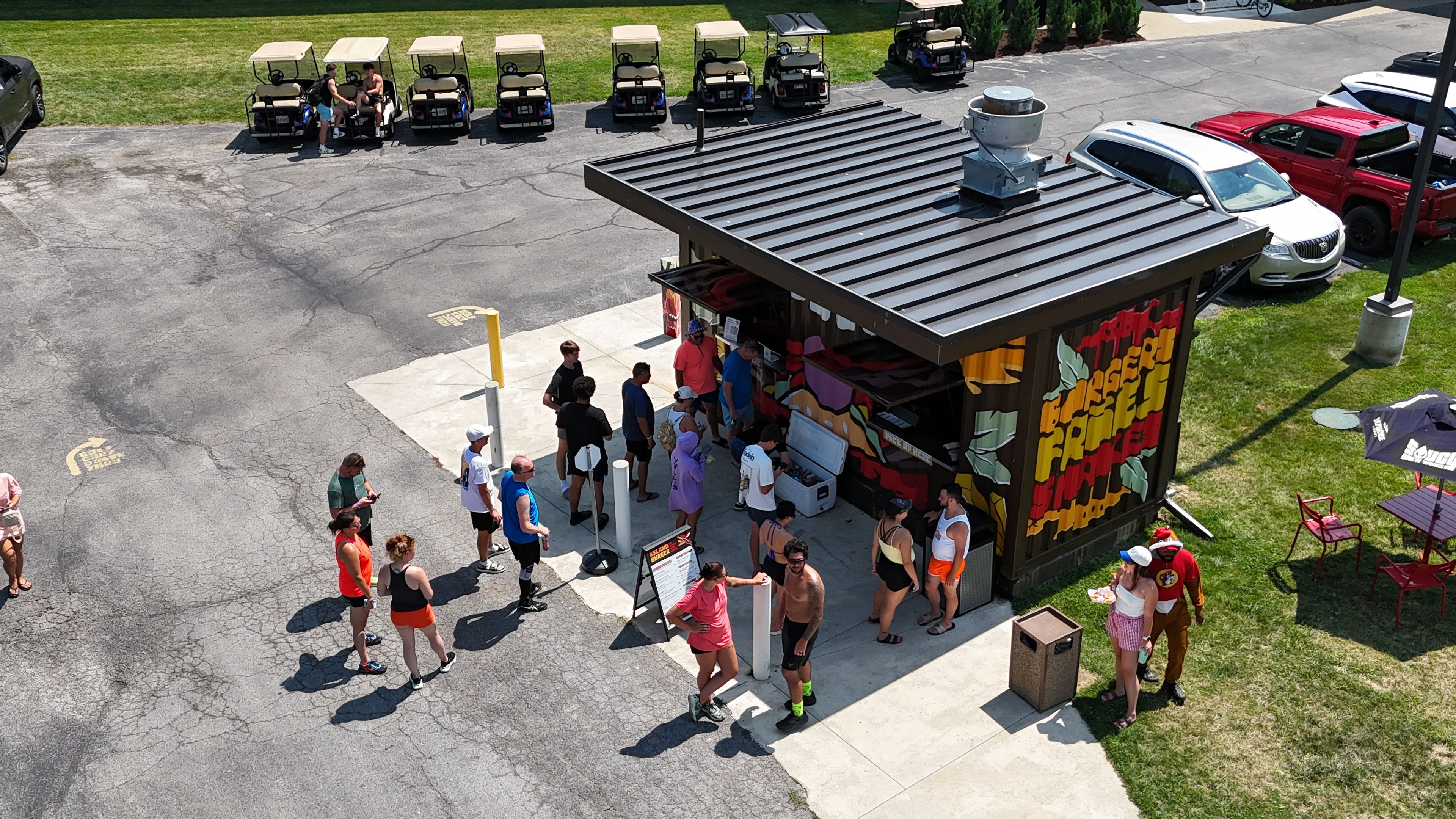 A food truck with a colorful exterior and a group of people gathered around it.