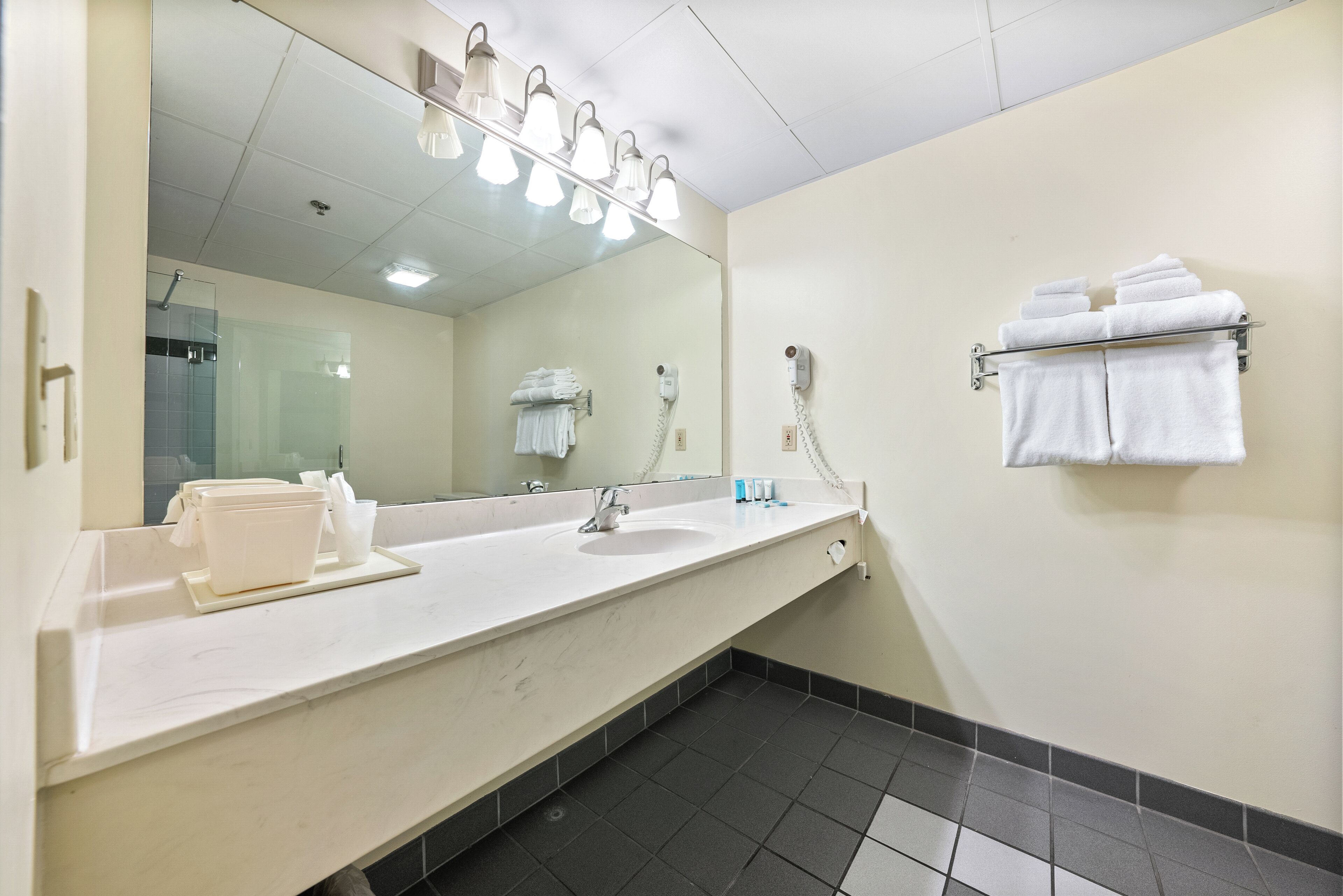 A hotel bathroom with a large mirror, a sink, and a towel rack.
