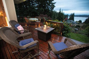 A wooden deck with wicker furniture and a fire pit.
